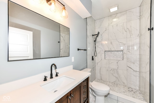 bathroom featuring tile patterned floors, vanity, tiled shower, and toilet