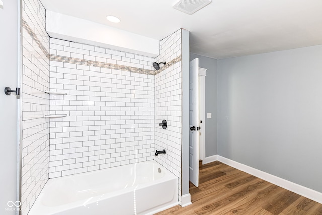 bathroom with hardwood / wood-style floors and tiled shower / bath