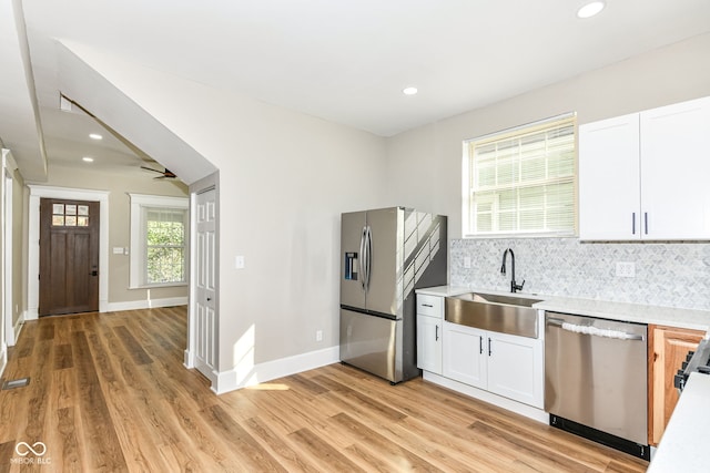 kitchen with stainless steel appliances, light hardwood / wood-style flooring, white cabinets, and sink