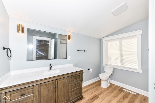 bathroom featuring wood-type flooring, vanity, lofted ceiling, and toilet