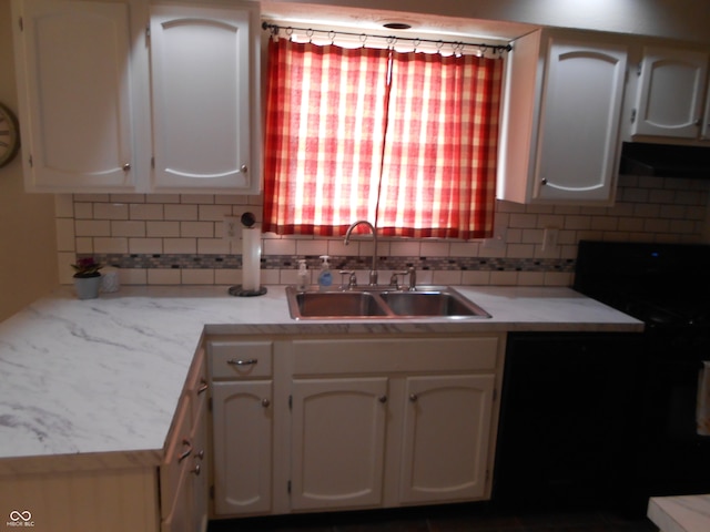 kitchen with white cabinets, black range oven, sink, and tasteful backsplash