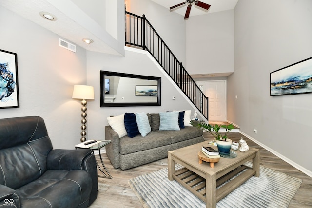 living room featuring a towering ceiling, ceiling fan, and light hardwood / wood-style flooring