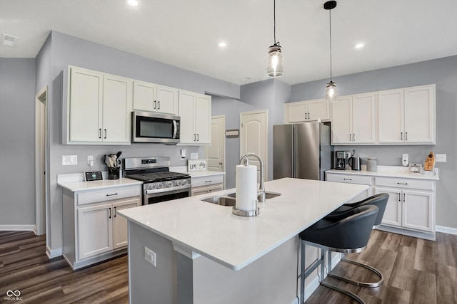 kitchen with white cabinets, stainless steel appliances, dark hardwood / wood-style floors, and an island with sink