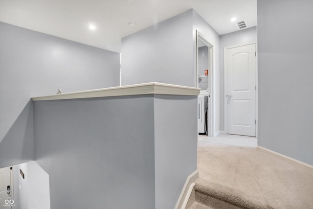 corridor with washer / clothes dryer and light carpet