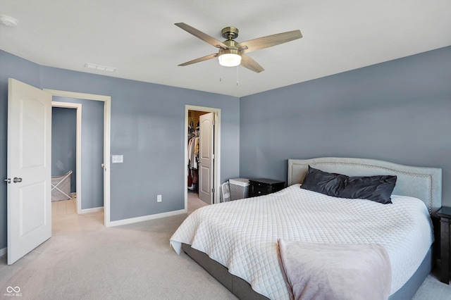 carpeted bedroom featuring ceiling fan, a closet, and a walk in closet