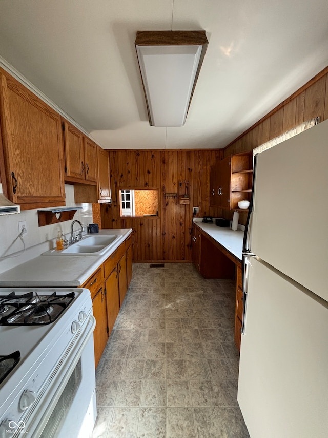 kitchen featuring pendant lighting, wood walls, sink, and white appliances