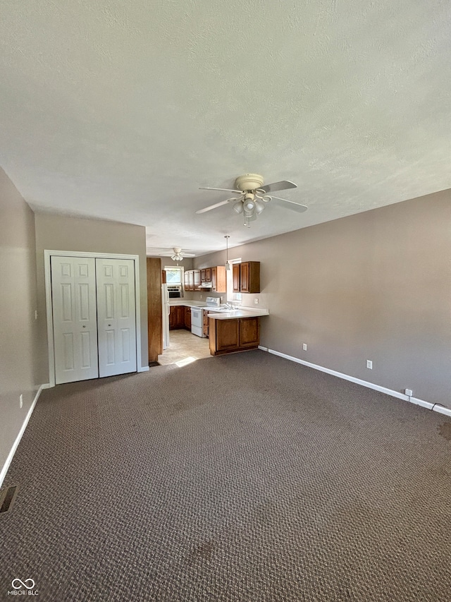 unfurnished living room with ceiling fan, a textured ceiling, and light carpet