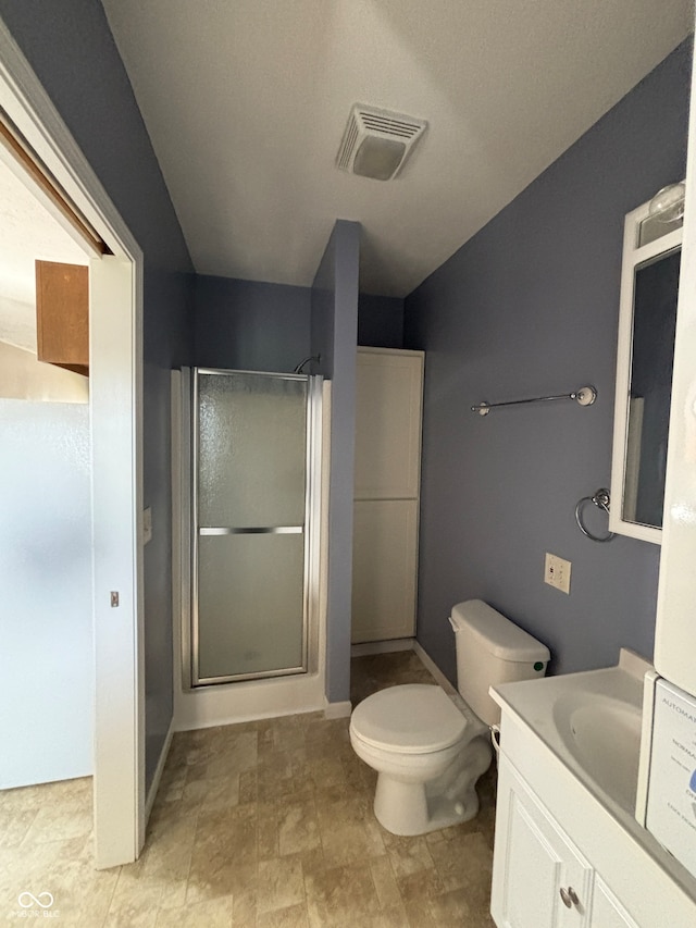 bathroom featuring vanity, a shower with shower door, and toilet