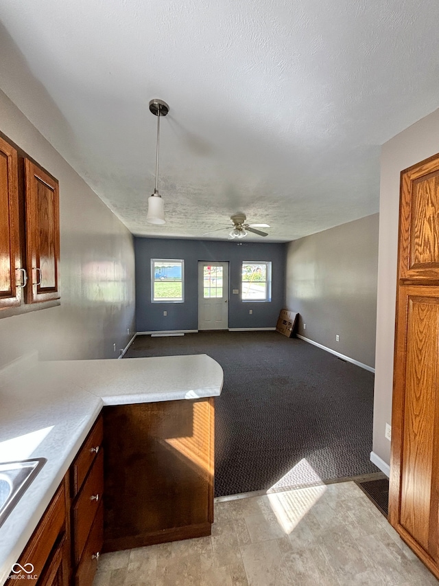 kitchen featuring ceiling fan, light carpet, sink, decorative light fixtures, and a textured ceiling