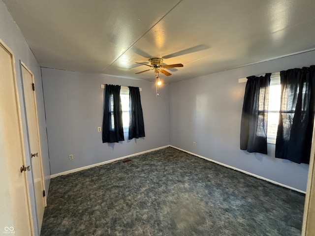 unfurnished room featuring dark carpet and ceiling fan