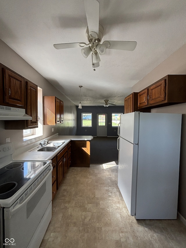 kitchen with pendant lighting, white appliances, a wealth of natural light, and a textured ceiling