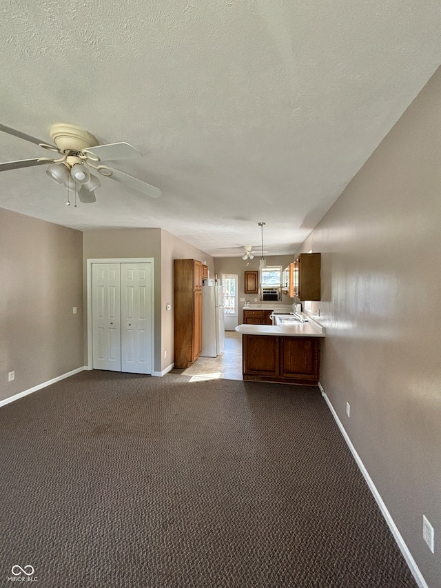 kitchen featuring kitchen peninsula, hanging light fixtures, light colored carpet, and white fridge