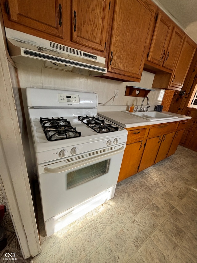 kitchen with sink, white gas stove, and tasteful backsplash