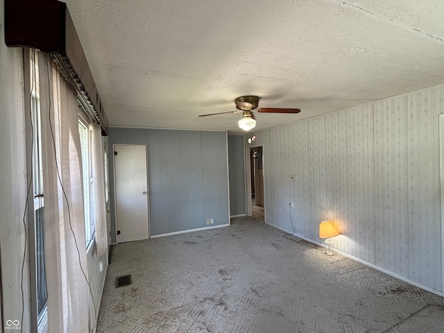 carpeted empty room featuring a textured ceiling and ceiling fan