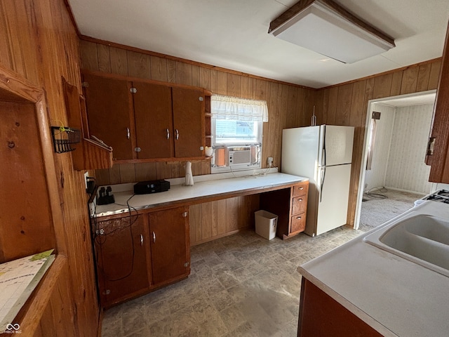 kitchen featuring wood walls, cooling unit, white fridge, and sink