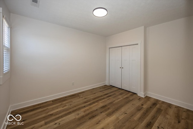 unfurnished bedroom featuring dark wood-type flooring and a closet