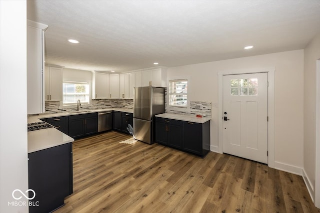 kitchen featuring white cabinets, tasteful backsplash, hardwood / wood-style floors, appliances with stainless steel finishes, and sink