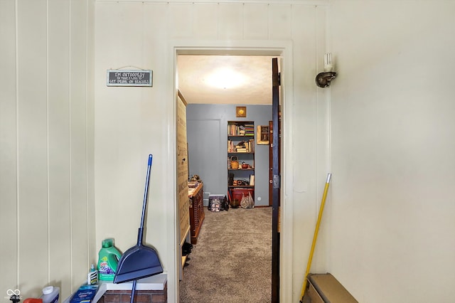 hallway featuring carpet flooring and wooden walls