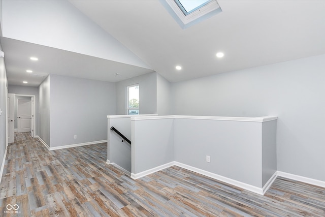 unfurnished room featuring vaulted ceiling with skylight and light wood-type flooring