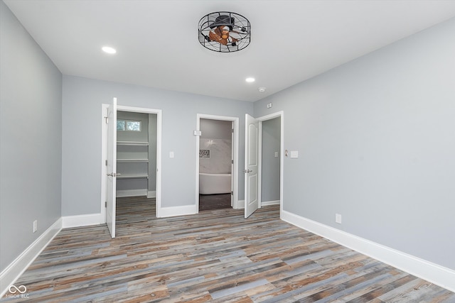 unfurnished bedroom featuring a spacious closet, connected bathroom, and light wood-type flooring