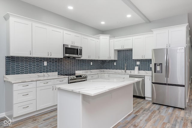 kitchen with backsplash, white cabinetry, stainless steel appliances, and light hardwood / wood-style floors