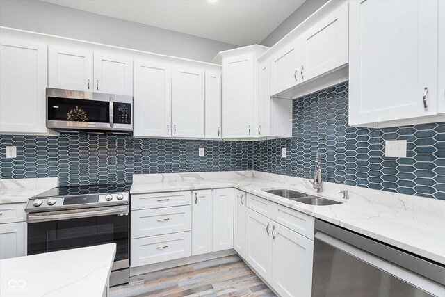 kitchen featuring stainless steel appliances, sink, light wood-type flooring, and white cabinets