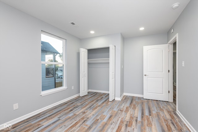 unfurnished bedroom with light hardwood / wood-style flooring and a closet