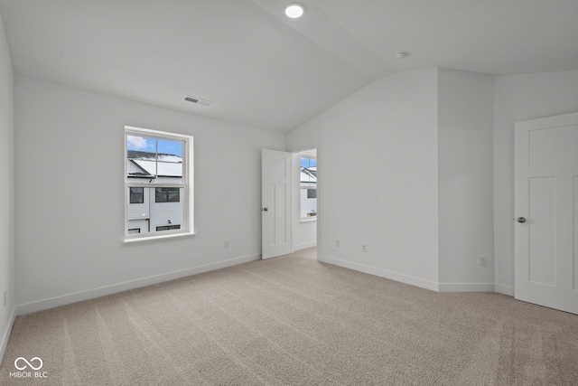 carpeted spare room with lofted ceiling