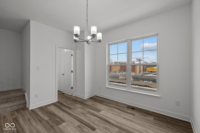 unfurnished dining area featuring a notable chandelier and wood-type flooring