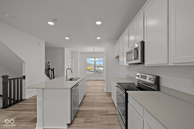 kitchen with white cabinets, stainless steel appliances, and light wood-type flooring