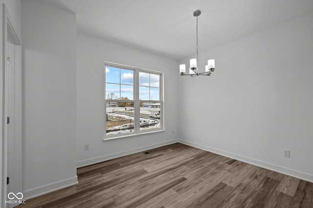 unfurnished dining area featuring hardwood / wood-style floors and a chandelier