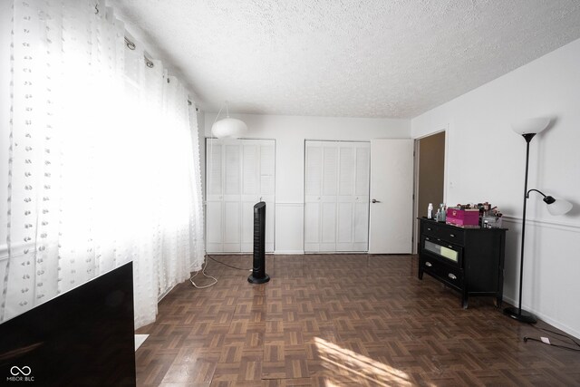 interior space featuring a textured ceiling and dark parquet flooring