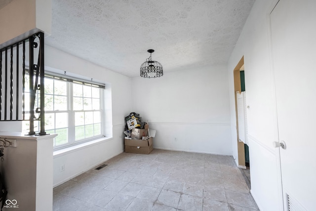 unfurnished dining area featuring a textured ceiling