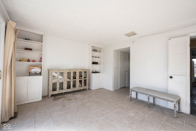 spare room featuring built in shelves and a textured ceiling