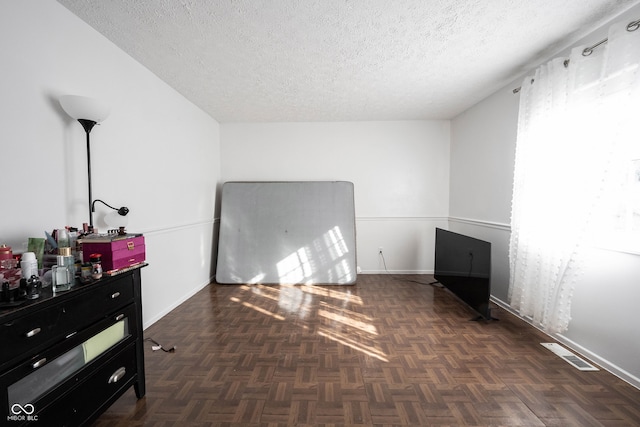 empty room with dark parquet floors and a textured ceiling