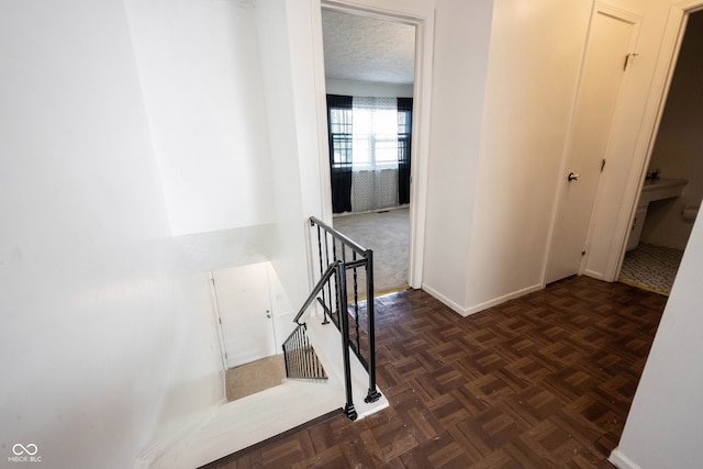 hallway with dark parquet flooring and a textured ceiling