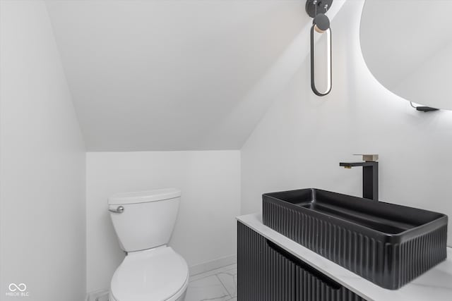 bathroom with toilet, lofted ceiling, and sink