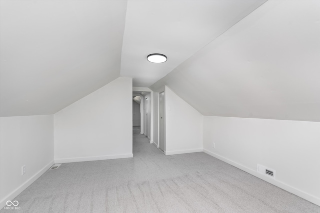 bonus room with light carpet and vaulted ceiling