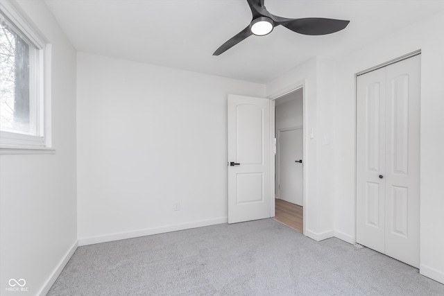 unfurnished bedroom with ceiling fan, light carpet, and a closet