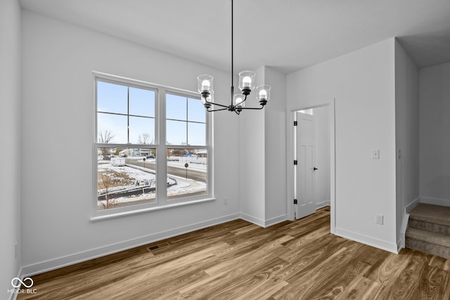 unfurnished dining area with hardwood / wood-style flooring and an inviting chandelier