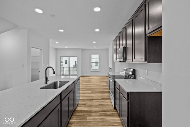 kitchen with hardwood / wood-style floors, sink, dark brown cabinets, light stone counters, and stainless steel appliances