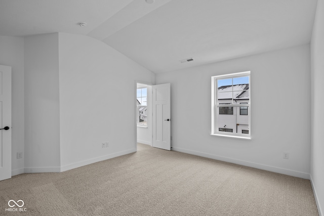 carpeted spare room with vaulted ceiling