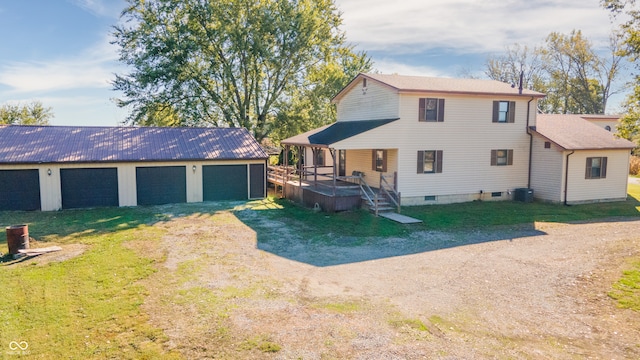 rear view of property featuring central air condition unit, a garage, a yard, and an outbuilding