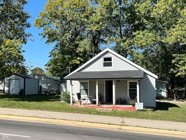 view of front facade featuring a porch, a storage unit, and a front lawn