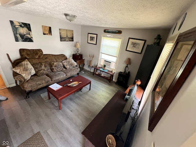 living room with cooling unit, a textured ceiling, wood-type flooring, and vaulted ceiling