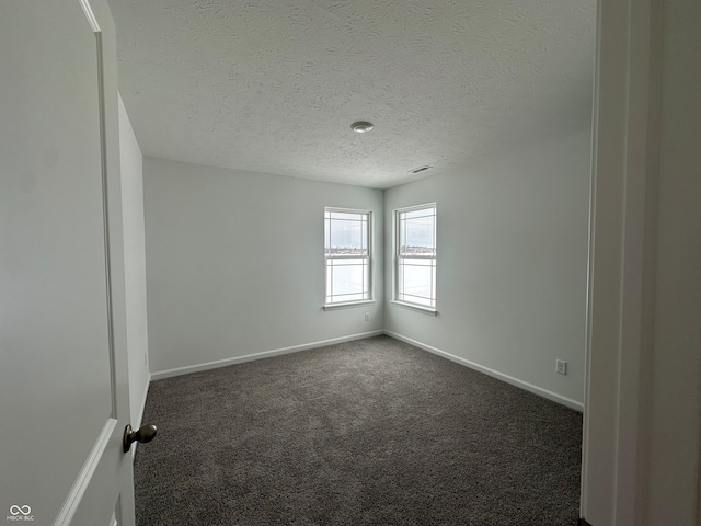 spare room with dark carpet and a textured ceiling