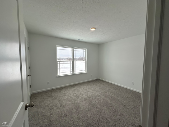 empty room featuring a textured ceiling and dark colored carpet