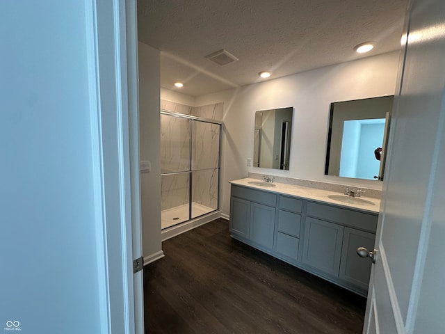 bathroom with vanity, hardwood / wood-style floors, a textured ceiling, and walk in shower