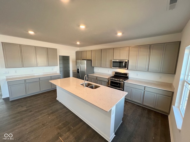 kitchen featuring sink, gray cabinetry, appliances with stainless steel finishes, dark hardwood / wood-style flooring, and a kitchen island with sink