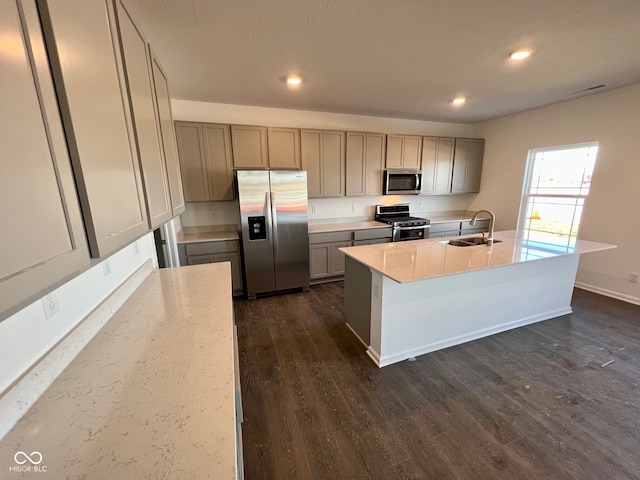 kitchen featuring sink, gray cabinets, appliances with stainless steel finishes, dark hardwood / wood-style floors, and an island with sink